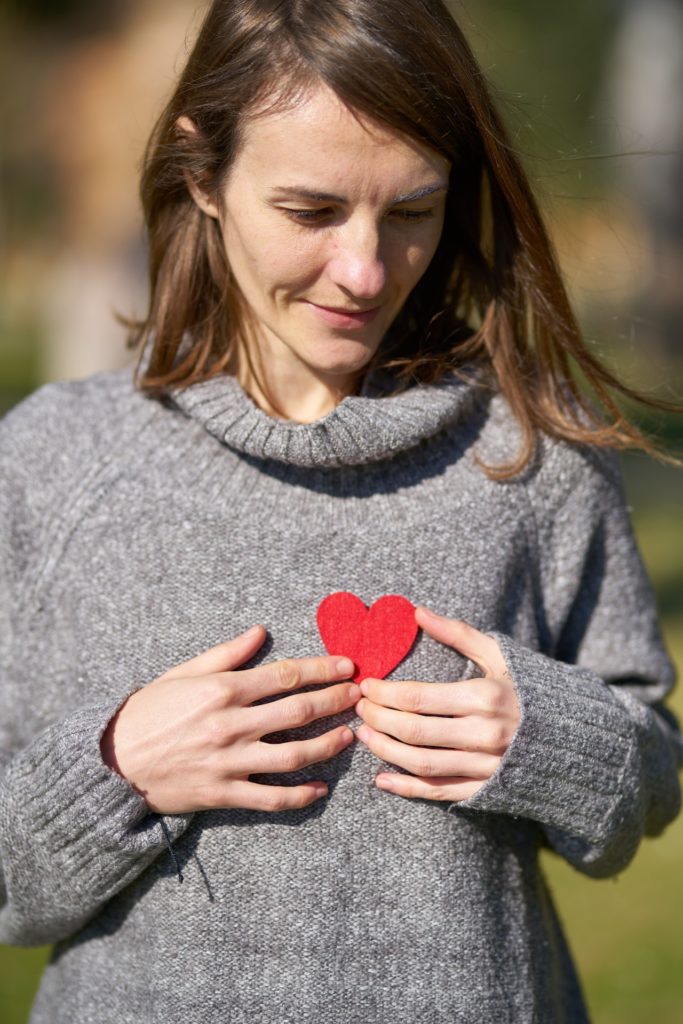 אישה מחזיקה לב אדום על עצמה